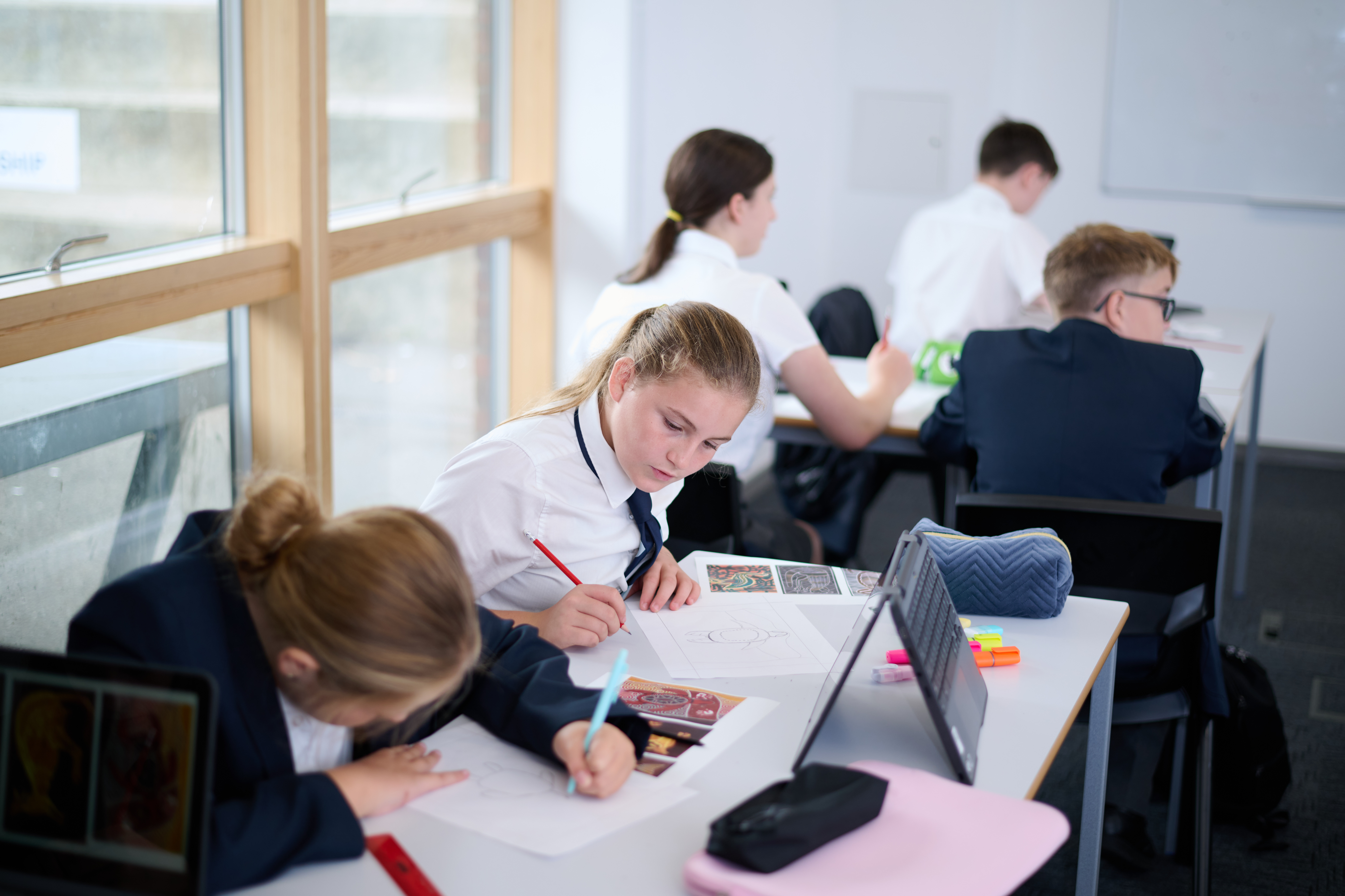 2 students at desks, drawing