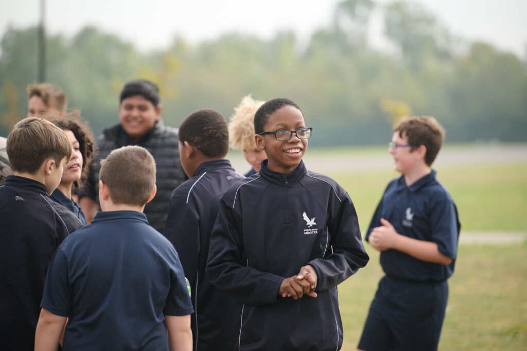 Students in PE kits, outside, talking and smiling