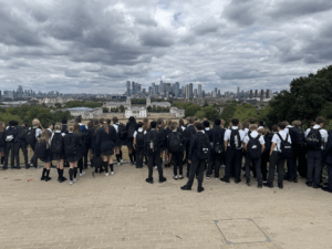A Group of students in school uniform look out from a hill across to the city of London