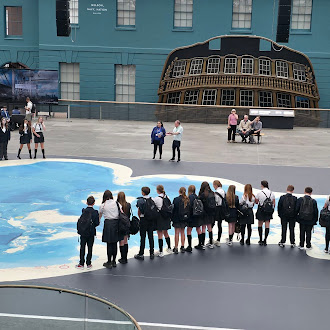 Pupils outside looking at a what looks like a large painted piece artwork on the ground